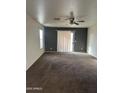 Bright living room with a ceiling fan, sliding glass door, neutral paint colors, and plush carpeting at 11521 W Charter Oak Rd, El Mirage, AZ 85335