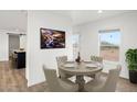 Charming dining room with a round table set for four, large windows, and modern art at 222 S Oak Rd, Maricopa, AZ 85139