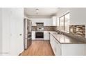 Bright kitchen featuring stainless steel appliances, white cabinets, and tiled backsplash at 7413 N 67Th Dr, Glendale, AZ 85303