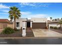 Charming single-story home with desert landscaping, palm tree and a two-car garage in a gated community at 10406 E Silvertree Dr, Sun Lakes, AZ 85248