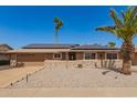 Charming single-story home featuring modern stone accents and solar panels against a bright blue sky at 10718 W Saratoga Cir, Sun City, AZ 85351