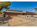 Inviting home with a wide driveway, stone accents, solar panels, and desert landscaping under a clear blue sky at 10718 W Saratoga Cir, Sun City, AZ 85351