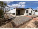 View of back exterior featuring a large covered patio, desert landscaping, and neutral siding at 10997 N Hualapai Dr, Casa Grande, AZ 85122