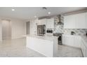 Bright kitchen with an island, white cabinets, stainless steel appliances, and marble tile floors at 21743 N Daniel Dr, Maricopa, AZ 85138