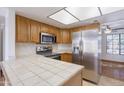 Bright kitchen showcasing tile countertops, stainless steel appliances, and ample wooden cabinet space at 2455 E Broadway Rd # 102, Mesa, AZ 85204