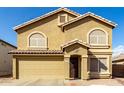 Inviting tan two-story home featuring arched windows, a tile roof, and a front-facing two-car garage at 2546 E Camellia Dr, Gilbert, AZ 85296