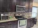 A close up of the dark wood cabinetry and stainless appliances in the kitchen at 2678 S 172Nd Dr, Goodyear, AZ 85338