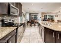 Bright kitchen featuring dark cabinetry, granite countertops, stainless appliances, and open dining area at 2678 S 172Nd Dr, Goodyear, AZ 85338