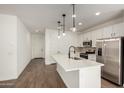Open kitchen featuring white cabinets, stainless steel appliances, a kitchen island with a sink, and modern pendant lighting at 11605 W Green Dr, Youngtown, AZ 85363