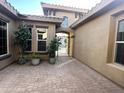 Private courtyard with brick pavers, mature plants, and a gated entrance to the main house at 1708 W Dusty Wren Dr, Phoenix, AZ 85085