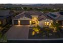 An eye-level view shows the facade of the house with its garage, well-lit driveway, and landscaped front yard at 18016 E Wolf Tree Ln, Rio Verde, AZ 85263