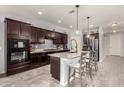 Modern kitchen with dark wood cabinets, granite countertops, a large kitchen island, and stainless steel appliances at 18146 W Tina Ln, Surprise, AZ 85387