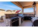 Outdoor kitchen with a built-in grill, stainless steel appliances, and a covered patio area perfect for entertaining at 18146 W Tina Ln, Surprise, AZ 85387