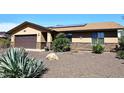 Single-story home showcasing desert landscaping, a two-car garage, and charming stone accents on the facade at 1920 E Manzanita Dr, Phoenix, AZ 85020