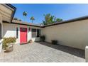 Inviting front entrance with a bright red door, lush landscaping, and a quaint tiled patio at 1974 E Vinedo Ln, Tempe, AZ 85284