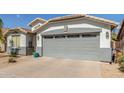 Two car garage featuring gray accents, exterior lighting, and xeriscaped front yard at 3284 W Five Mile Peak Dr, San Tan Valley, AZ 85144