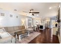 Bright, open-concept living room with dark wood floors, modern furnishings, ceiling fan and seamless flow to kitchen at 7428 W Montgomery Rd, Peoria, AZ 85383