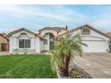 Well-manicured lawn and desert landscaping highlight this single-story home with a tile roof at 7543 E Keats Ave, Mesa, AZ 85209