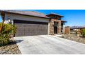 Stylish single-level home with a stone-accented entrance, two-car garage, and desert landscaping for easy care at 8836 S 165Th Ave, Goodyear, AZ 85338