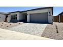 Inviting single-story home featuring a gray driveway and low-maintenance desert landscaping at 22685 E Saddle Way, Queen Creek, AZ 85142