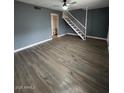 Spacious living room with modern wood flooring, ceiling fan, and staircase at 2551 W Berridge Ln # D6, Phoenix, AZ 85017