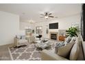 Bright living room with a cozy fireplace, ceiling fan, and neutral furniture at 2560 E Indian Wells Pl, Chandler, AZ 85249