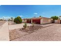 Charming single-story home showcasing a landscaped front yard with a red garage door and decorative concrete block accents at 6305 E Adobe Rd, Mesa, AZ 85205