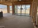 View of the home's unfinished interior, featuring framed walls, large glass sliding doors, and concrete flooring at 7694 W Saddlehorn Rd, Peoria, AZ 85383