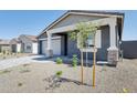 Charming home featuring a two-car garage and a xeriscaped front yard with young tree at 7701 W Avenida Del Rey --, Peoria, AZ 85383
