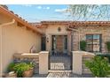 Close-up of a stone and stucco entrance with an iron gate and a decorative wooden front door at 7915 E Stonecliff Cir, Mesa, AZ 85207