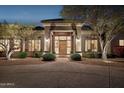 Inviting front entrance with elegant stone columns, a beautiful wood door, and manicured landscaping at 13126 E Turquoise Ave, Scottsdale, AZ 85259