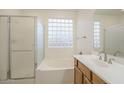 Well-lit bathroom with a tub, glass-enclosed shower, and vanity with a sink at 18624 E Cattle Dr, Queen Creek, AZ 85142