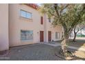 Charming townhouse exterior with tidy landscaping and a shade tree near the entrance at 4625 W Thomas Rd # 19, Phoenix, AZ 85031