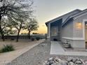 View of the home's exterior with desert landscaping, an extended driveway, and a well-lit entrance at 9644 N 97Th Ln, Peoria, AZ 85345