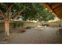 Spacious brick-paved patio featuring mature shade trees, an outdoor seating area, string lights, and privacy walls at 1041 E Orangewood Ave, Phoenix, AZ 85020