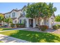 Inviting front exterior showcases a well-manicured lawn, mature tree, and a charming gray and white two-story home at 10451 E Natal Ave, Mesa, AZ 85209