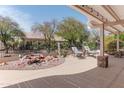 Beautiful backyard with a serene rock water feature, complemented by mature trees and comfortable lounge chairs at 2612 N 161St Ave, Goodyear, AZ 85395