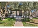 Attractive home featuring a gray exterior, a pink front door, a well-kept lawn, and mature trees providing ample shade at 348 W Portland St, Phoenix, AZ 85003