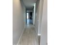 A long hallway with light wood-look flooring, neutral paint and access to the kitchen at 43387 N Wollemi St, Queen Creek, AZ 85140