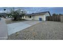 View of home's exterior features a two-car garage, mature trees, and desert landscaping at 4416 E Capistrano Ave, Phoenix, AZ 85044