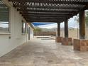 Covered patio overlooking pool and landscaped backyard boasts travertine tile and exposed wood beams at 4416 E Capistrano Ave, Phoenix, AZ 85044