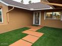 Inviting front entrance with lush synthetic grass, a secure screen door, and a modern pathway at 4807 E Everett Dr, Scottsdale, AZ 85254