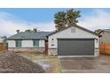 Charming exterior view with a gray two-car garage door, stone accents, and ample driveway space at 6812 S 41St Pl, Phoenix, AZ 85042