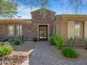 Elegant home entrance featuring custom stone work and landscaped walkway at 10829 E Volterra Ct, Scottsdale, AZ 85262