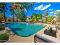 Inviting backyard pool with lounge seating, mature trees, and blue skies above at 1205 W El Prado Rd, Chandler, AZ 85224