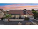 Rear exterior view showcasing covered patio with block privacy wall and well-maintained tile roof at 13942 W Summerstar Dr, Sun City West, AZ 85375