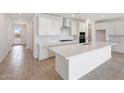 Modern, all-white kitchen featuring stainless steel appliances, quartz countertops, and a large kitchen island at 17253 W Via Dona Rd, Surprise, AZ 85387