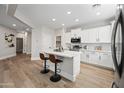 Spacious kitchen featuring an island with seating, stainless steel appliances, white cabinets, and hardwood flooring at 2196 E Brigadier Dr, Gilbert, AZ 85298