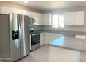 Renovated kitchen with stainless steel appliances, a center island, and gray countertops at 2632 E Irwin Ave, Mesa, AZ 85204