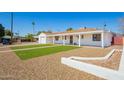 Home exterior with white paint, desert landscaping, a strip of grass and covered porch at 3028 E Highland Ave, Phoenix, AZ 85016